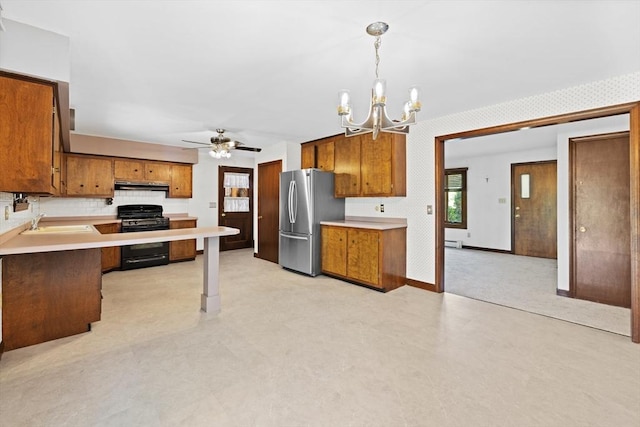 13 Abraham Ave, Freetown, MA 02717 - kitchen with black gas stove, freestanding refrigerator, a chandelier, brown cabinetry, and range hood