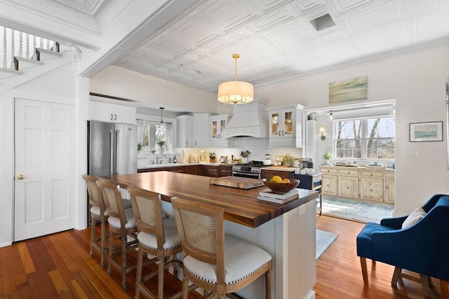 kitchen featuring custom exhaust hood, an ornate ceiling, butcher block counters, and stainless steel appliances