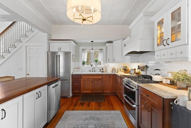 kitchen with dark wood finished floors, decorative backsplash, an ornate ceiling, stainless steel appliances, and a sink