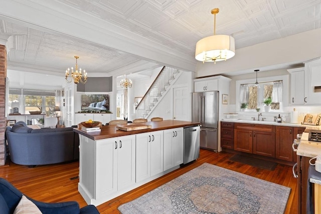 kitchen with a notable chandelier, open floor plan, an ornate ceiling, and stainless steel appliances