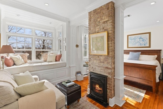 interior space featuring wood finished floors, visible vents, a fireplace, recessed lighting, and ornamental molding