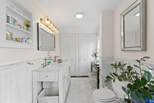 bathroom with a wainscoted wall, toilet, and vanity