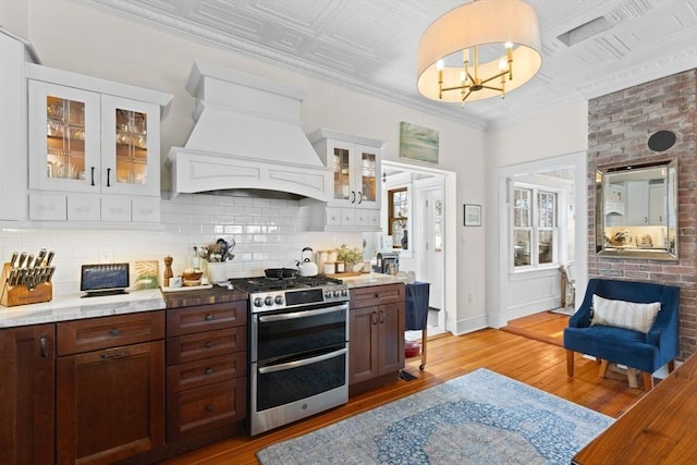 kitchen with tasteful backsplash, crown molding, double oven range, custom exhaust hood, and an ornate ceiling