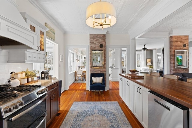 kitchen featuring glass insert cabinets, dark wood-type flooring, custom range hood, appliances with stainless steel finishes, and wood counters