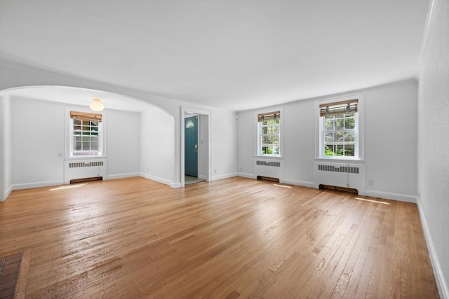 191 Speen, Natick, MA 01760 - unfurnished living room with radiator heating unit, arched walkways, and light wood-style floors