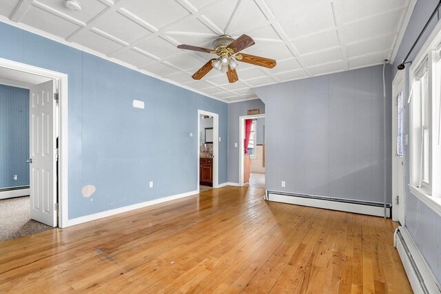 spare room with a wealth of natural light, light wood-style flooring, a baseboard heating unit, and a ceiling fan