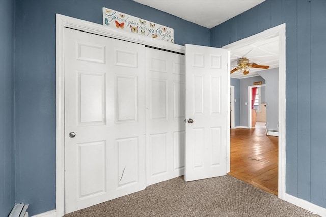 unfurnished bedroom featuring a baseboard heating unit, a closet, carpet, and baseboards