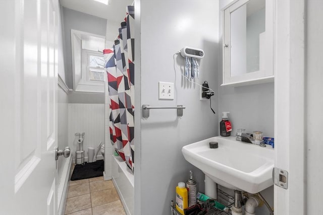 full bath with shower / bath combo with shower curtain, a sink, and tile patterned floors