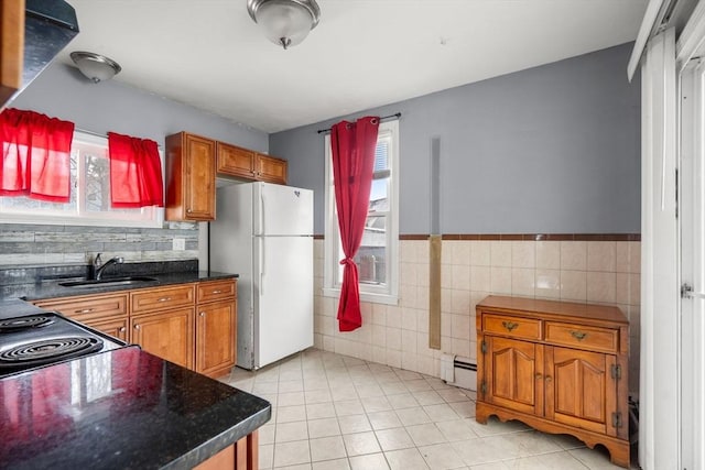 kitchen featuring brown cabinetry, freestanding refrigerator, a sink, and dark countertops