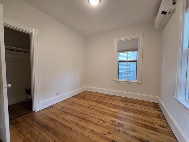98 Boylston St Unit 1, Brookline, MA 02445 - unfurnished bedroom featuring wood-type flooring, a wall unit AC, and baseboards