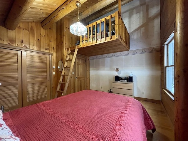 bedroom with beamed ceiling, wood-type flooring, multiple windows, and wood walls