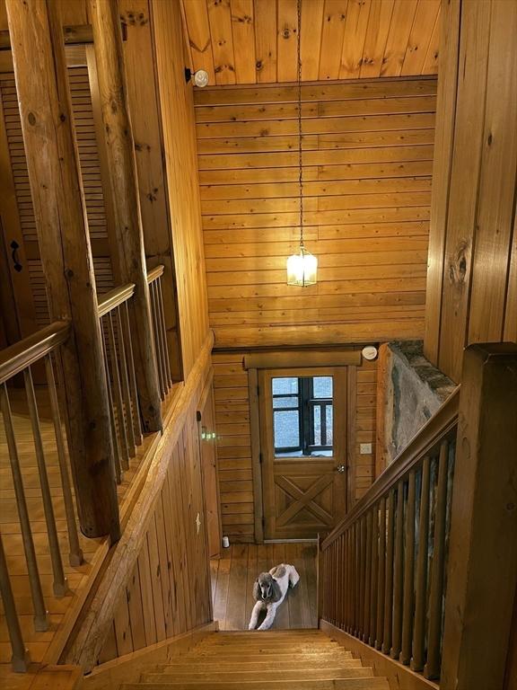 stairs featuring hardwood / wood-style floors and wood walls