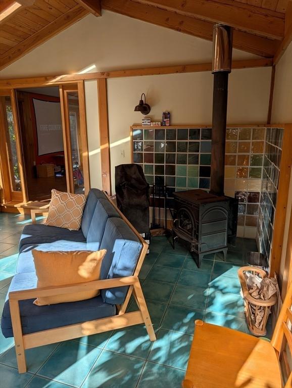 interior space featuring vaulted ceiling with beams, a wood stove, and wood ceiling