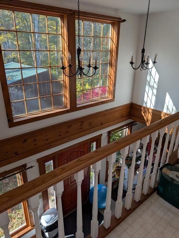 stairs featuring a wealth of natural light and an inviting chandelier