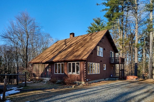 view of property exterior with a sunroom and a balcony