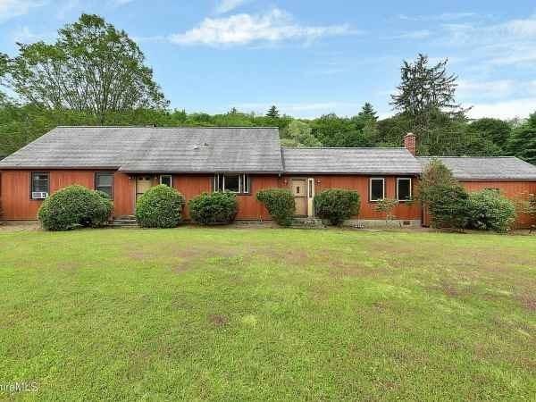 ranch-style home with a chimney and a front lawn