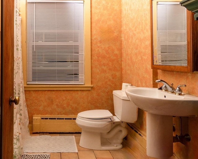 bathroom featuring a baseboard heating unit, toilet, and tile patterned floors