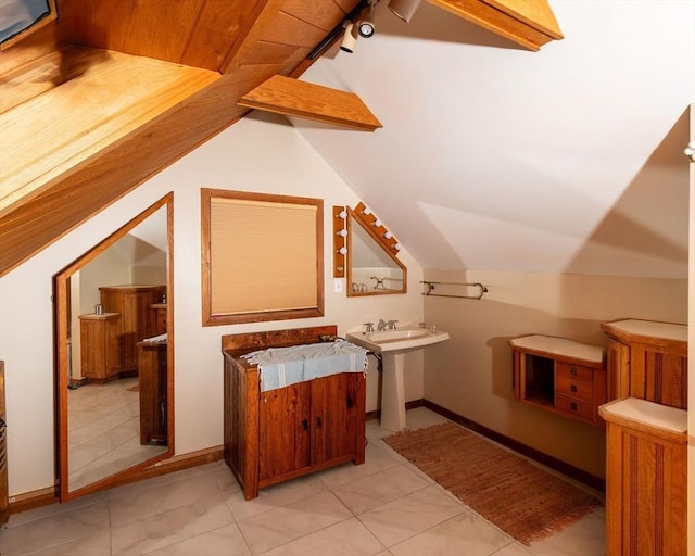 bonus room with lofted ceiling with beams and baseboards