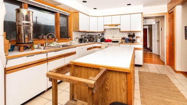 kitchen with under cabinet range hood, white appliances, a sink, white cabinets, and light countertops