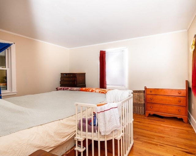 bedroom with light wood finished floors and crown molding