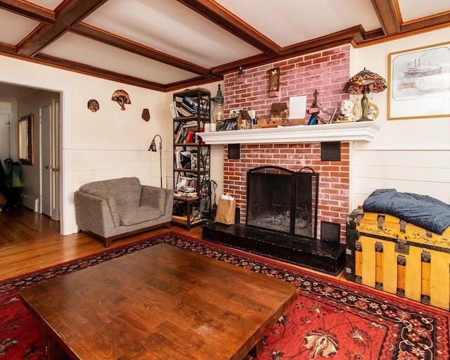 living room with crown molding, a fireplace, beamed ceiling, and wood finished floors