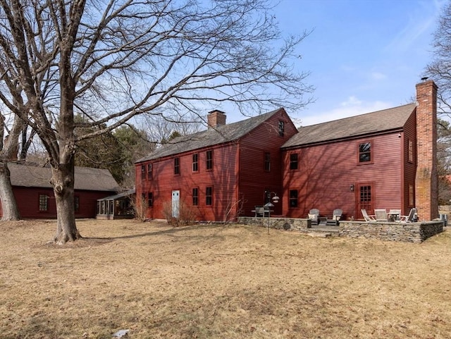 view of side of home featuring a chimney, a patio area, and a lawn