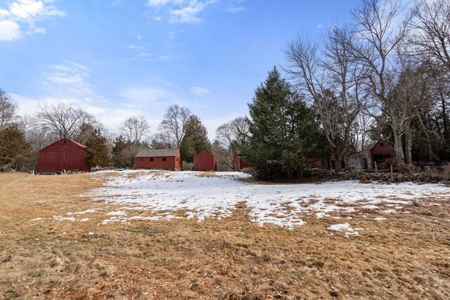 yard layered in snow featuring a barn and an outbuilding