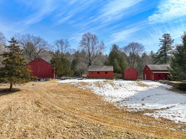 yard covered in snow with an outdoor structure and a barn