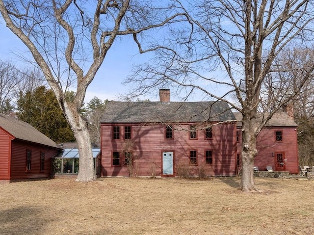 rear view of property with a chimney and a yard