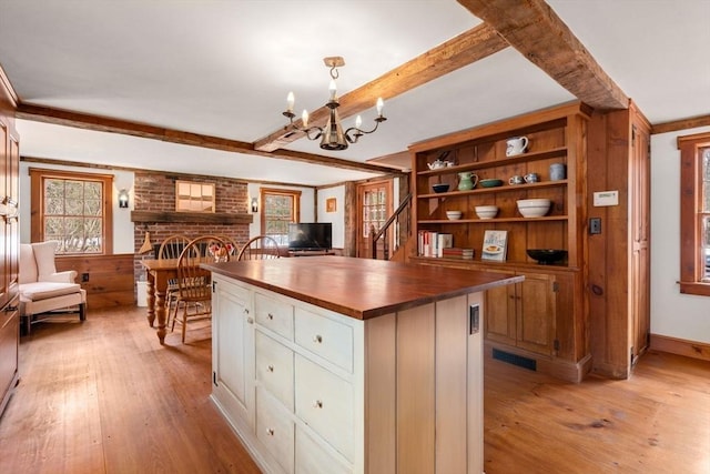 kitchen featuring a fireplace, visible vents, butcher block countertops, light wood-type flooring, and beamed ceiling