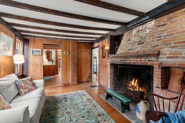 living area with wood walls, a fireplace, wood finished floors, visible vents, and beamed ceiling