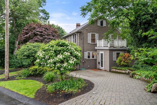 24 Aspen Ave, Newton, MA 02466 - view of front of home with a chimney, a balcony, curved driveway, and a patio