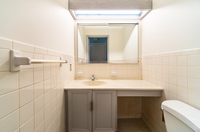 bathroom featuring tile walls, wainscoting, vanity, and toilet