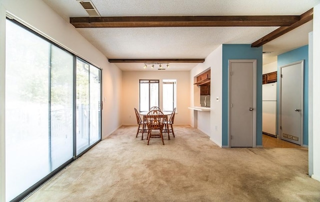 dining space with a textured ceiling, visible vents, beamed ceiling, and light colored carpet