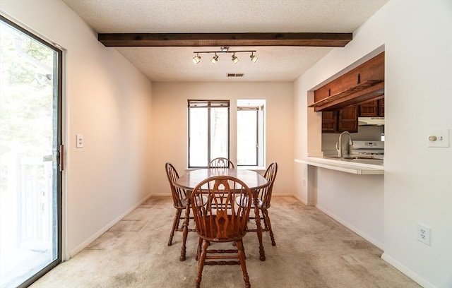 dining area with beam ceiling, a wealth of natural light, visible vents, light colored carpet, and a textured ceiling