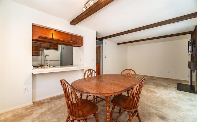 dining space with baseboards, beam ceiling, and light colored carpet