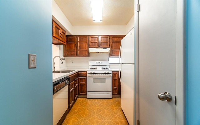 kitchen with under cabinet range hood, white appliances, a sink, light countertops, and light floors