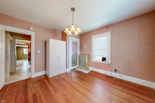 interior space featuring a chandelier, light wood finished floors, and a textured ceiling