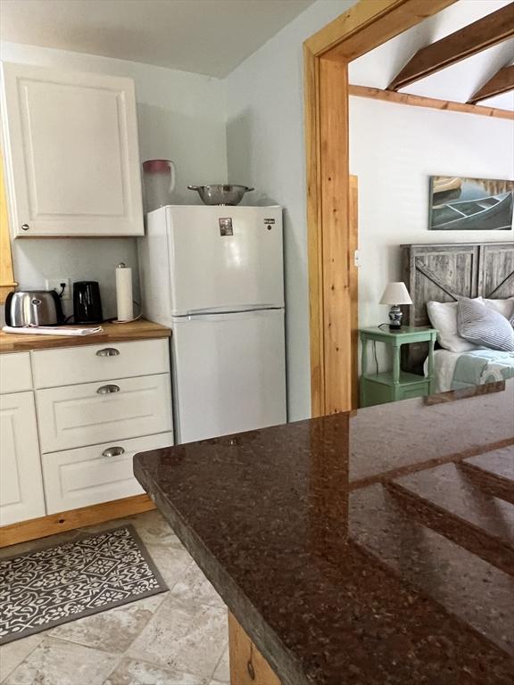 10 Kibbe Point Rd, Otis, MA 01253 - kitchen featuring freestanding refrigerator, white cabinets, and dark stone counters