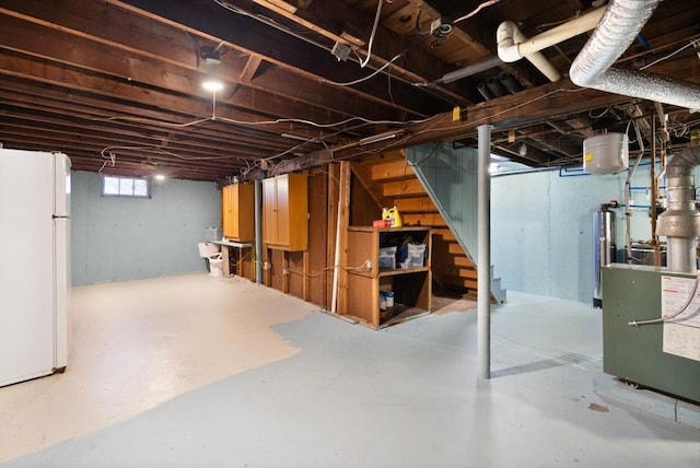 basement featuring water heater and white fridge