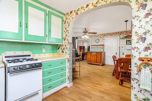 119 Clark St, Clinton, MA 01510 - kitchen with white gas range oven, wallpapered walls, a ceiling fan, light wood finished floors, and arched walkways