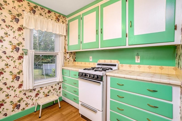 119 Clark St, Clinton, MA 01510 - kitchen with white gas range oven, wallpapered walls, light wood finished floors, and tile counters