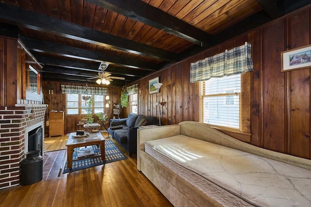 bedroom featuring wood ceiling, wood-type flooring, wooden walls, beamed ceiling, and a fireplace