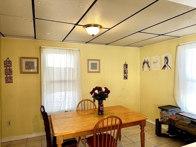 tiled dining space featuring wooden walls