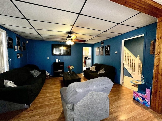 living room featuring hardwood / wood-style flooring, a paneled ceiling, and ceiling fan