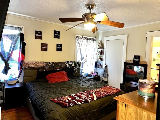 bedroom with hardwood / wood-style flooring, ceiling fan, ornamental molding, and a textured ceiling