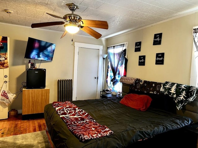 bedroom with ceiling fan, ornamental molding, radiator heating unit, and wood-type flooring