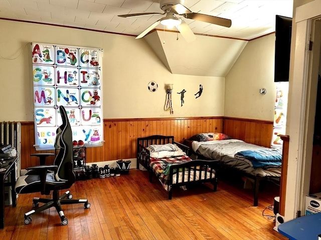 bedroom with lofted ceiling, wood-type flooring, ceiling fan, and wood walls