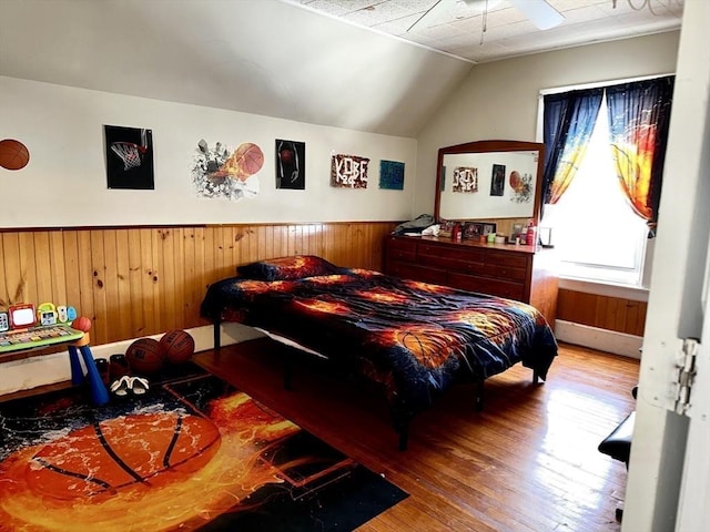 bedroom featuring wood-type flooring, vaulted ceiling, and wood walls