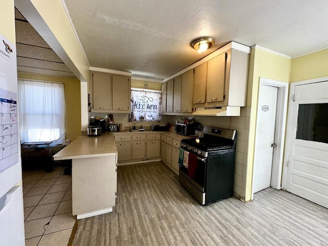 kitchen featuring light brown cabinetry, sink, stainless steel gas stove, kitchen peninsula, and decorative backsplash